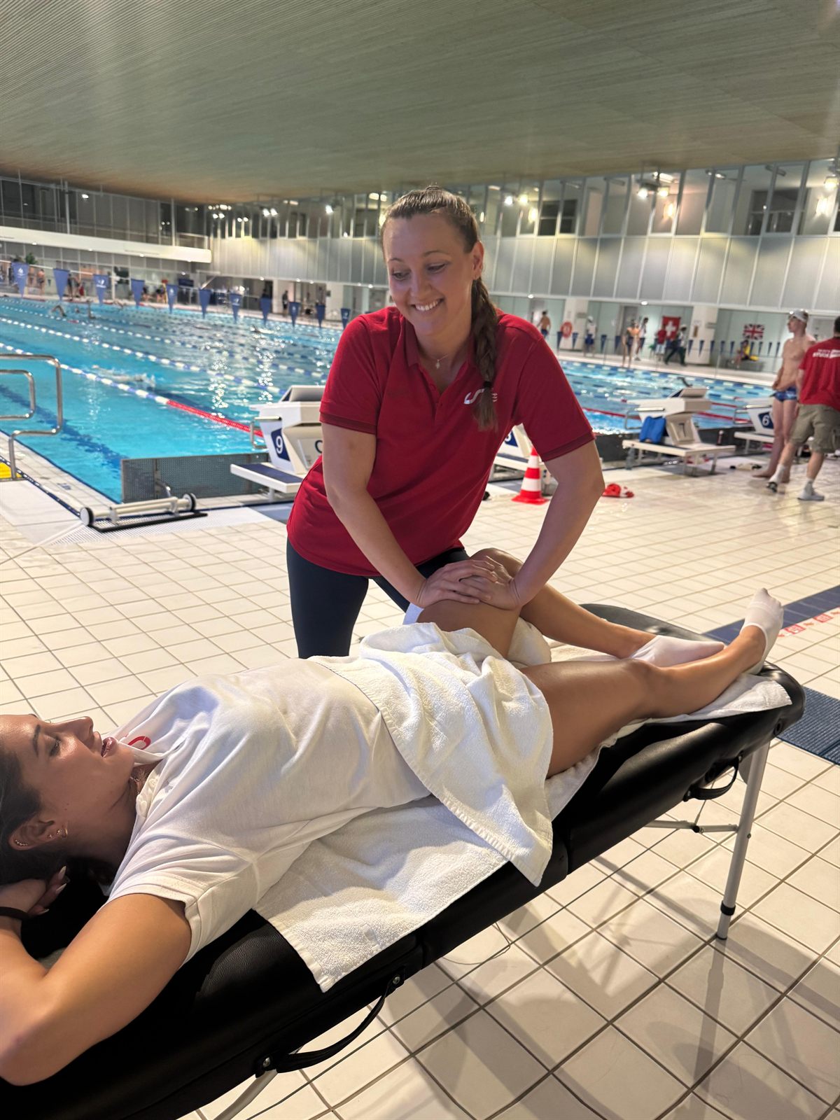 Melani realizando fisioterapia deportiva a una nadadora junto a la piscina